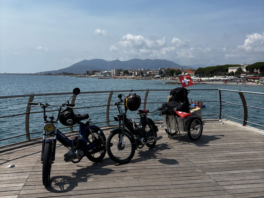 Die zwei Mofas mit Anhänger und Schweizer Fahne am Meer